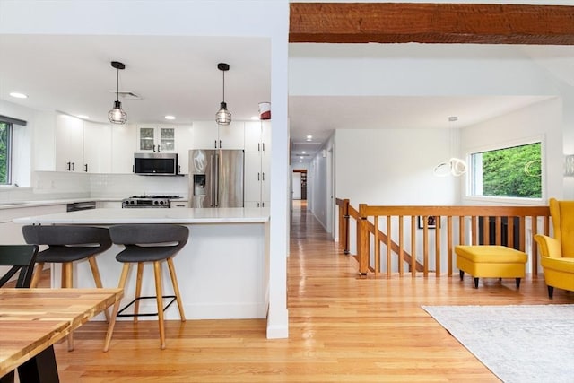 10 Longmeadow Ln, Medway, MA 02053 - kitchen with stainless steel appliances, light wood-style floors, a breakfast bar area, light countertops, and white cabinets