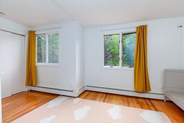 10 Longmeadow Ln, Medway, MA 02053 - unfurnished bedroom featuring multiple windows, wood finished floors, baseboard heating, and a closet