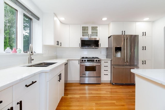 10 Longmeadow Ln, Medway, MA 02053 - kitchen featuring appliances with stainless steel finishes, decorative backsplash, white cabinets, light wood finished floors, and recessed lighting