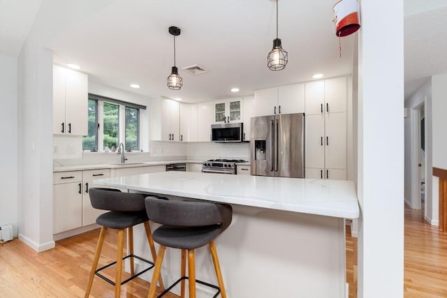 10 Longmeadow Ln, Medway, MA 02053 - kitchen with stainless steel appliances, light wood-style flooring, tasteful backsplash, a kitchen bar, and recessed lighting
