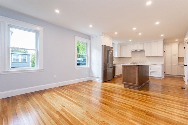 kitchen with a kitchen island, high quality fridge, white cabinets, and light hardwood / wood-style flooring