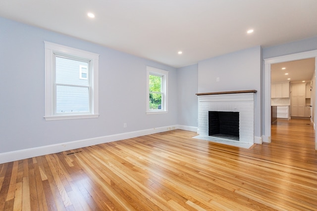 unfurnished living room featuring a fireplace and light hardwood / wood-style flooring