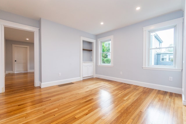 spare room featuring light wood-type flooring and plenty of natural light