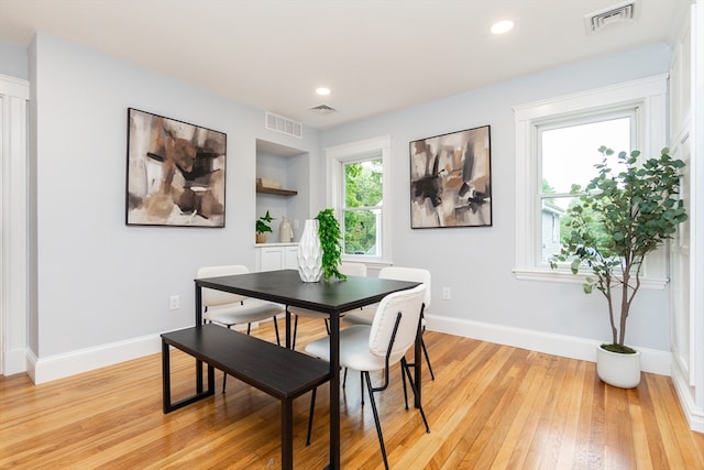 dining area with light wood-type flooring and built in features