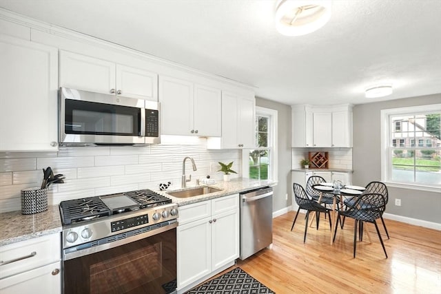 132 Nelson St, West Springfield, MA 01089 - kitchen with appliances with stainless steel finishes, white cabinets, light wood-type flooring, backsplash, and light stone countertops