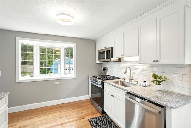132 Nelson St, West Springfield, MA 01089 - kitchen with appliances with stainless steel finishes, tasteful backsplash, light wood-style flooring, white cabinets, and light stone countertops