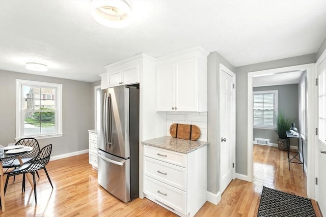 132 Nelson St, West Springfield, MA 01089 - kitchen featuring freestanding refrigerator, light wood finished floors, white cabinets, light stone counters, and healthy amount of natural light