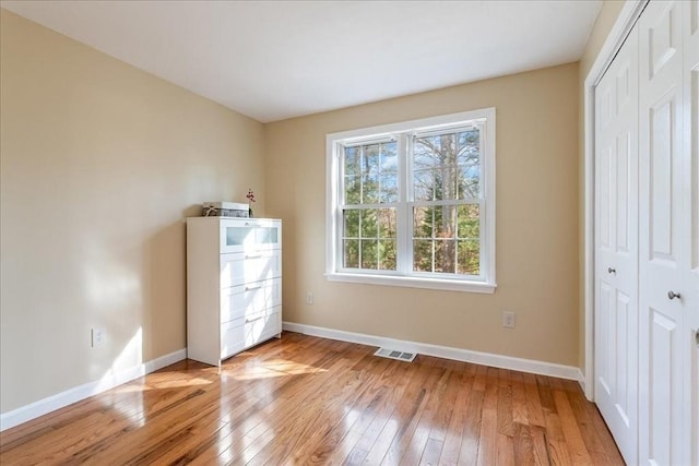 unfurnished bedroom with visible vents, baseboards, light wood-style floors, and a closet