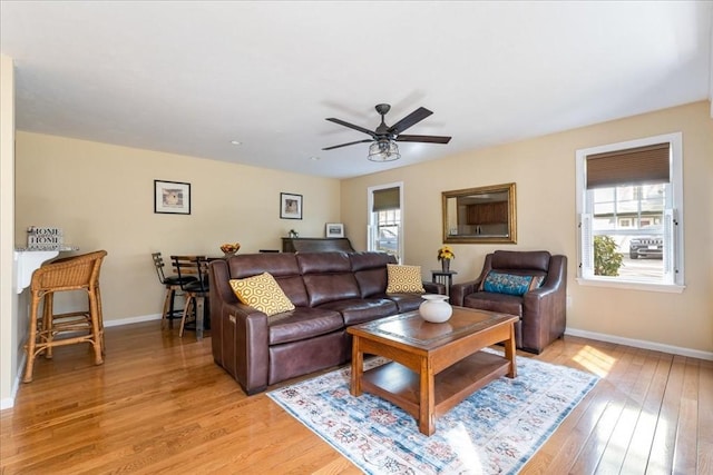 living room featuring light wood-type flooring, baseboards, and ceiling fan