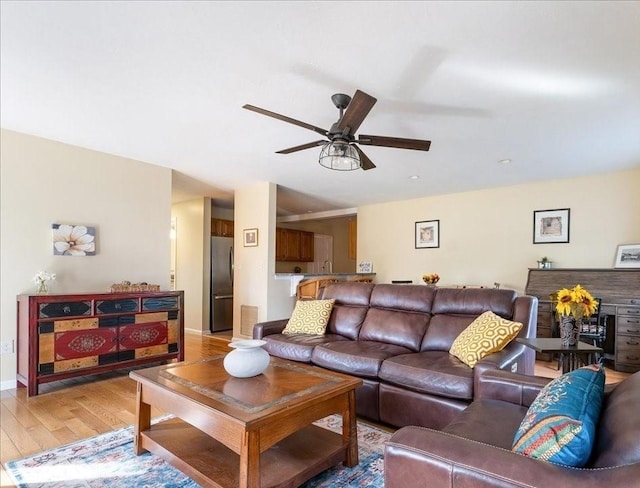 living room with visible vents, light wood-style flooring, and ceiling fan