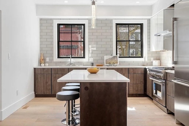 kitchen featuring sink, light hardwood / wood-style flooring, tasteful backsplash, a kitchen island, and stainless steel appliances