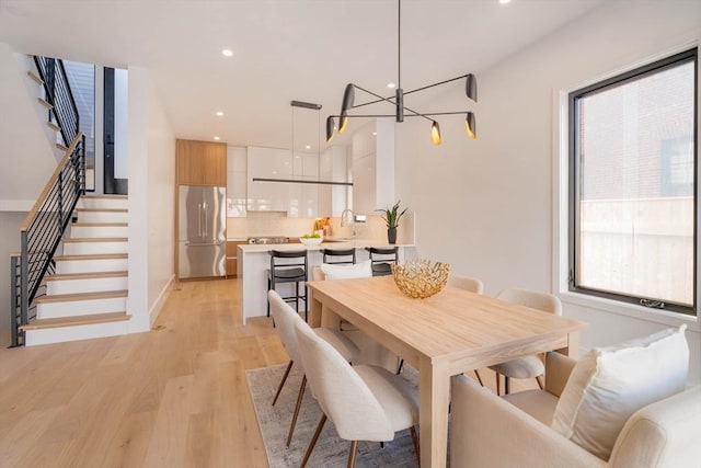 dining space featuring light hardwood / wood-style floors, sink, and an inviting chandelier