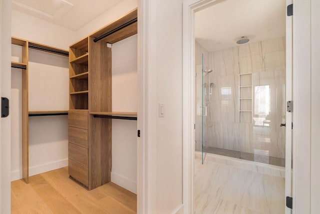 walk in closet with light hardwood / wood-style floors and elevator