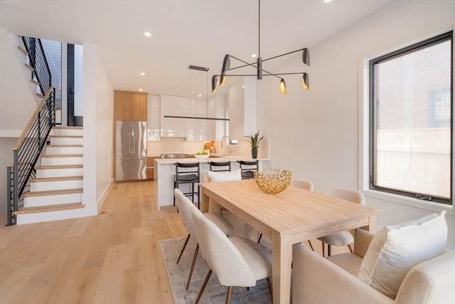 dining space featuring a chandelier, light hardwood / wood-style flooring, and sink