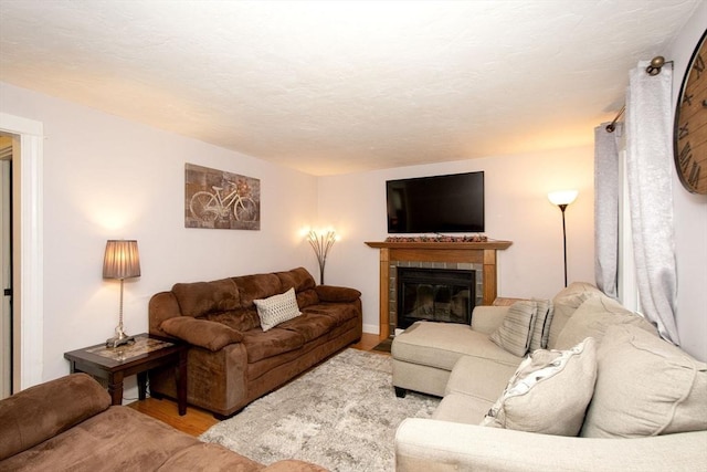 living room featuring light wood-type flooring and a tiled fireplace