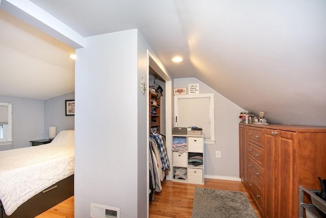 bedroom featuring hardwood / wood-style flooring, vaulted ceiling, and a closet