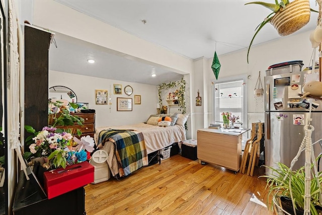 bedroom with light wood-style flooring and freestanding refrigerator