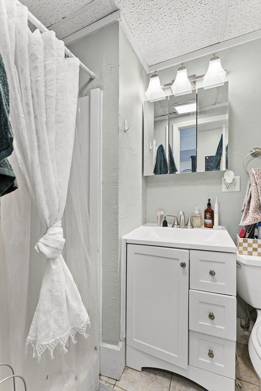 bathroom featuring a shower with curtain, tile patterned floors, toilet, and vanity