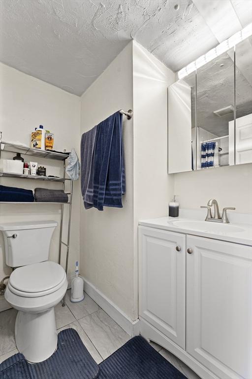 bathroom with baseboards, marble finish floor, toilet, and vanity