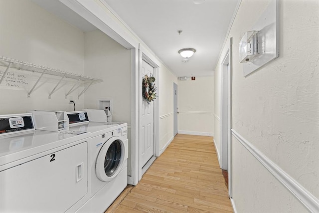 shared laundry area with light wood-style flooring, a textured wall, and separate washer and dryer