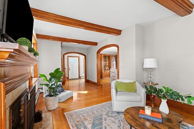 3 Scotland Heights Rd, Haverhill, MA 01832 - living room featuring arched walkways, beam ceiling, light wood-style floors, a fireplace with flush hearth, and baseboards
