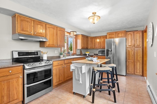 3 Scotland Heights Rd, Haverhill, MA 01832 - kitchen featuring under cabinet range hood, stainless steel appliances, a baseboard radiator, brown cabinetry, and a breakfast bar area