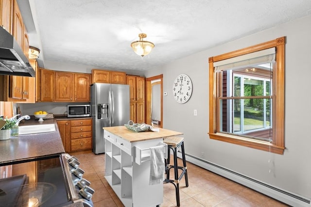 3 Scotland Heights Rd, Haverhill, MA 01832 - kitchen with appliances with stainless steel finishes, baseboard heating, wall chimney exhaust hood, a sink, and light tile patterned flooring