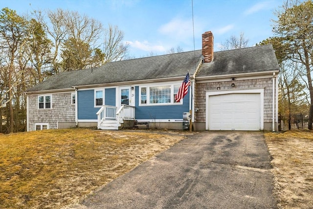 view of front of house with aphalt driveway, an attached garage, a chimney, and roof with shingles