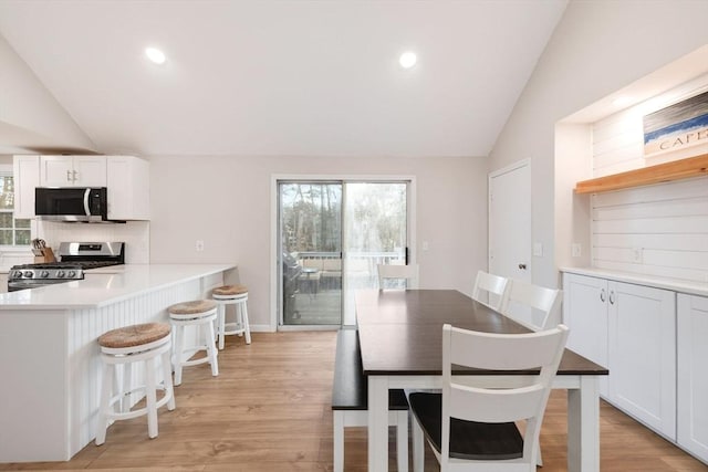 dining area with lofted ceiling, light wood-style flooring, and recessed lighting