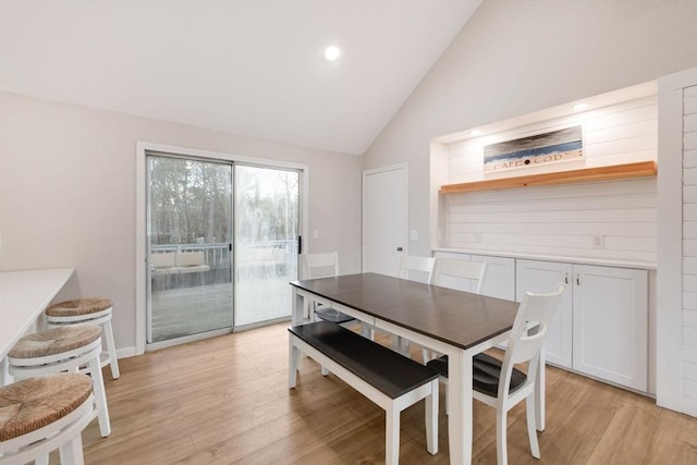 dining room with light wood-style flooring and vaulted ceiling