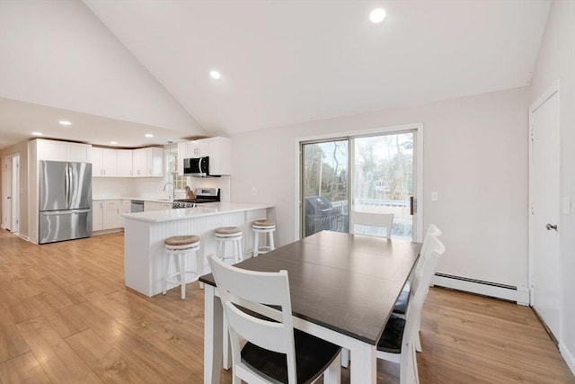 dining room with recessed lighting, a baseboard radiator, high vaulted ceiling, and light wood-style flooring