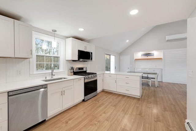 kitchen featuring a baseboard heating unit, a wall unit AC, appliances with stainless steel finishes, a peninsula, and a sink