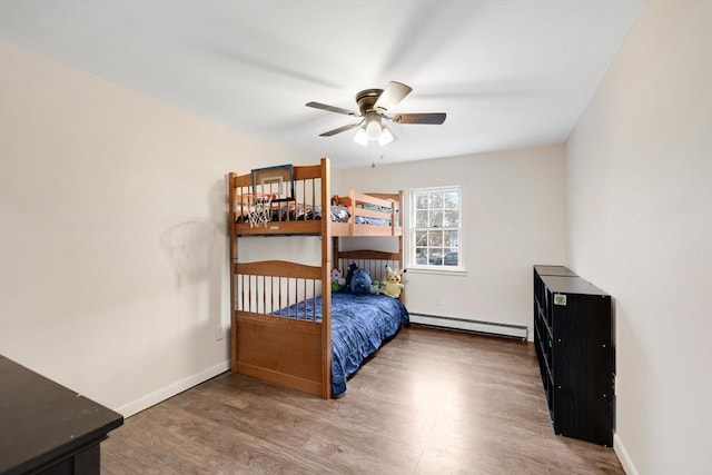 bedroom with baseboard heating, a ceiling fan, baseboards, and wood finished floors