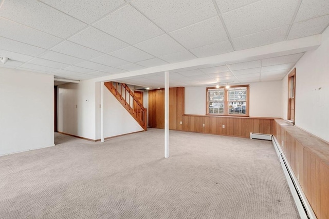 basement with wooden walls, carpet flooring, stairs, and a baseboard radiator