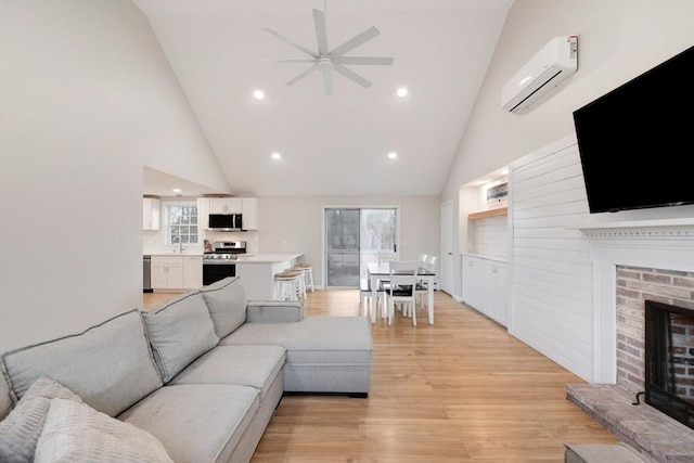 living area with a wealth of natural light, a fireplace, light wood-type flooring, and a wall mounted air conditioner