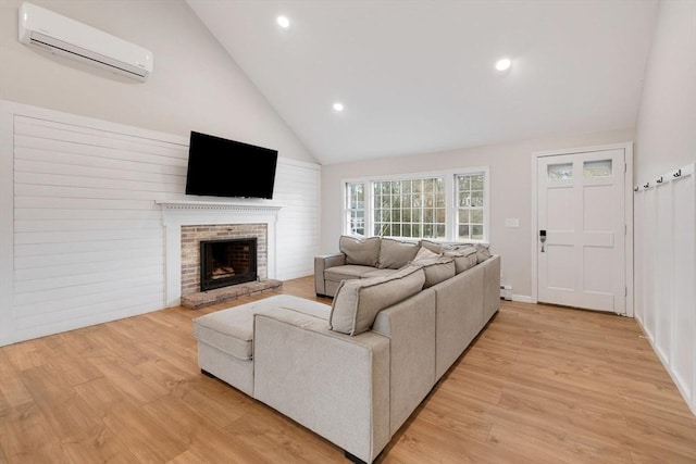 living room featuring high vaulted ceiling, a fireplace, an AC wall unit, and light wood-type flooring