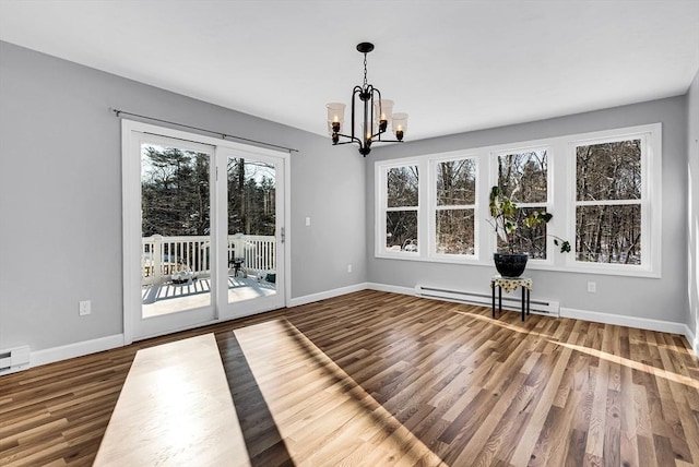 unfurnished dining area with an inviting chandelier, wood-type flooring, and baseboard heating