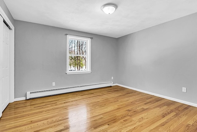 empty room with a baseboard heating unit and light hardwood / wood-style flooring