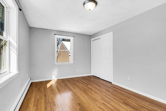 unfurnished room with a baseboard heating unit and light hardwood / wood-style flooring