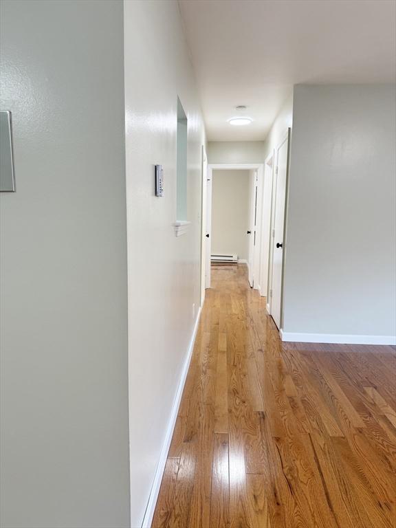 hall with a baseboard radiator and light wood-type flooring