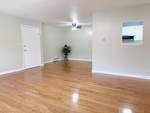 empty room featuring ceiling fan, light hardwood / wood-style floors, and a baseboard heating unit