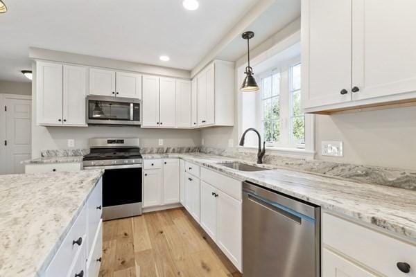 kitchen featuring white cabinets, recessed lighting, stainless steel appliances, a sink, and light wood-style floors