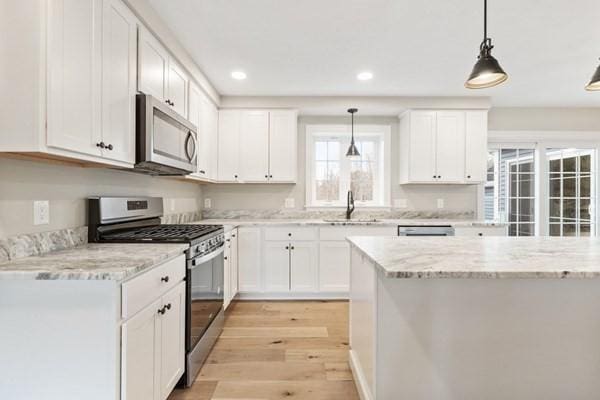 kitchen with light wood-style flooring, white cabinetry, stainless steel appliances, and a sink