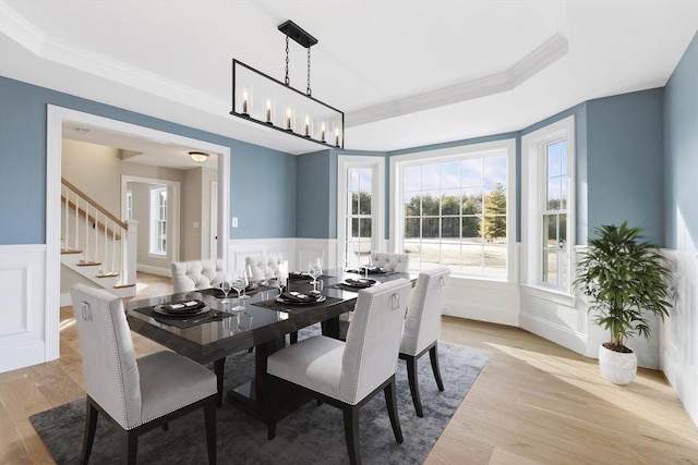 dining space with a decorative wall, a wainscoted wall, and a raised ceiling