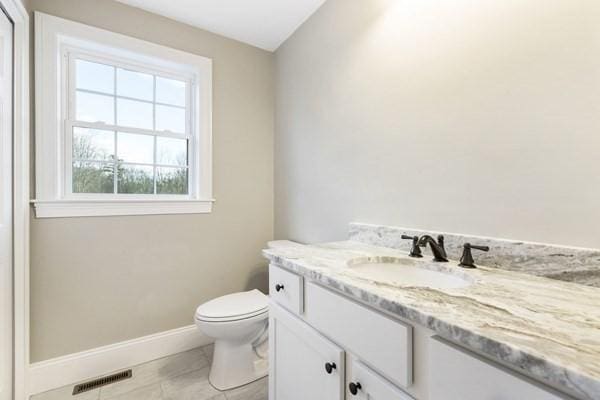 bathroom with a wealth of natural light, toilet, vanity, and baseboards