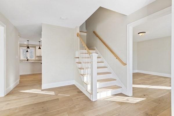 stairs with wood finished floors and baseboards