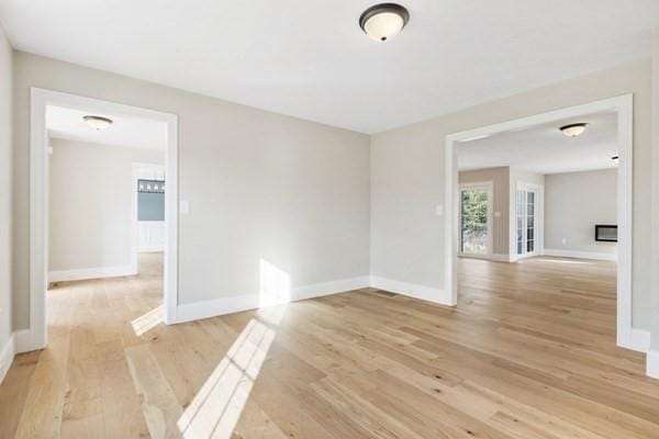 unfurnished room with light wood-type flooring and baseboards