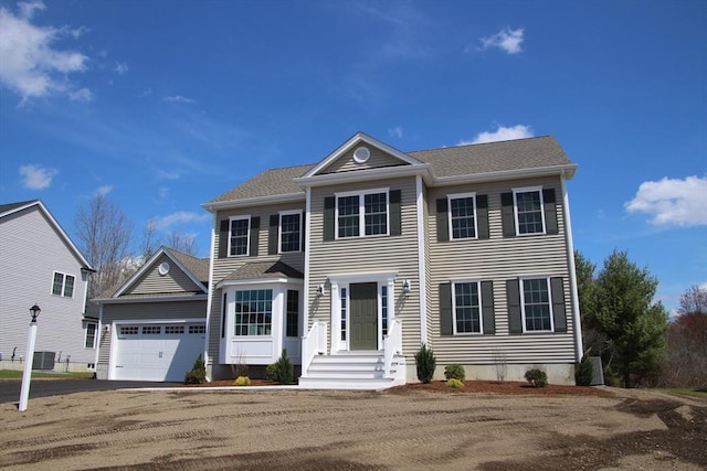 colonial-style house featuring a garage and aphalt driveway