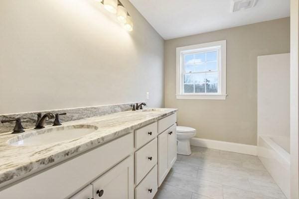 full bath with double vanity, toilet, baseboards, and a sink