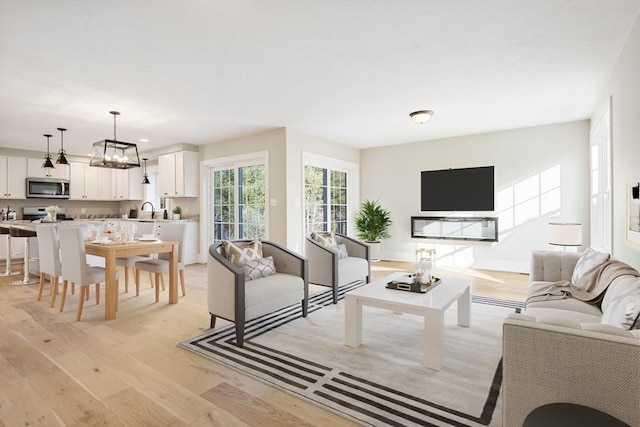 living room featuring light wood finished floors, baseboards, and a notable chandelier
